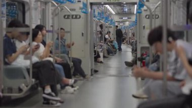 Güney Kore, Seul - 10 Temmuz 2025: Seul 'deki günlük metro gezileri sırasında, kalabalık bir trende oturan ve rutin toplu taşıma araçlarını sergileyen banliyö sakinleri