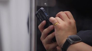 Taipei metrosunda bir elinde metal metro direği, diğer elinde akıllı telefon tutan adamın ağır çekim hareketi.