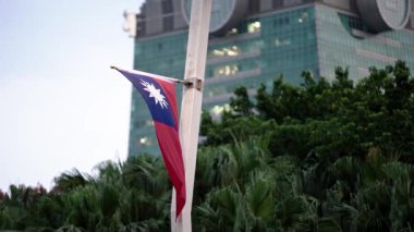 Tayvan bayrağının yavaş hareketi kısmen ağaç dallarıyla gizlenmiş, doğayla iç içe vatanseverliği simgeliyor..