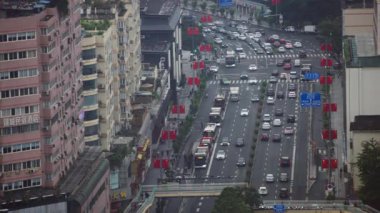 Chengdu, Çin-11 Ekim 2024: Chengdu 'da yüksek konut binalarıyla dolu dar bir cadde boyunca dolu arabaların tepeden aşağı yavaş görüntüsü