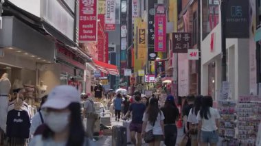 Seul, Güney Kore-10 Temmuz 2025: Myeongdong alışveriş bölgesinin dar sokaklarında yürüyen insanlar, canlı vitrinler, kırmızı işaretler ve ticari bir akış ile dolu.