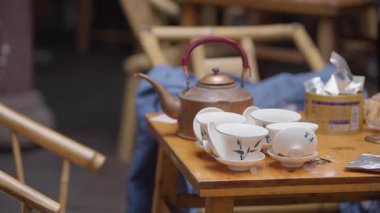 Chengdu 'daki ahşap bir masada çay tepsisi ve uzun soluklu çaydanlığın yavaş çekimleri rafine çay kültürünün atmosferini yakalıyor.