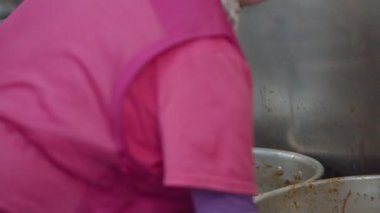 Pembe üniformalı Koreli satıcının yoğun öğle yemeği saatinde Seouls Gwangjang Market 'te büyük kepçeyle çorba karıştırması..