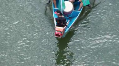 Taipei, Tayvan-08 Haziran 2024: Taipei kürekçisinin yavaş hareketi gölün içine odaklanmış sakin, altın güneş ışığı altında dikiz aynasıyla kürek çekmesi.