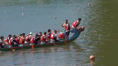 Taipei, Tayvan-08 Haziran 2024: Rıhtımın yanında yavaşça kürek çeken Taipei kürekçisinin yavaş hareketi, yansımaları ve ılık günbatımı renkleriyle yan görüş.