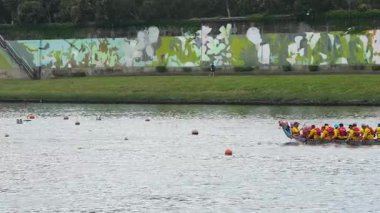 Taipei, Tayvan-08 Haziran 2024: Durgun göle doğru kürek çeken Taipei kürekçisinin yavaş hareketi, suyun üzerinde altın saat yansıması ile tam bir görünüm yakaladı..