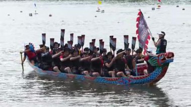 Taipei, Tayvan-08 Haziran 2024: Taipei kürekçisinin yavaş hareketi, küreği yavaşça kaldırıyor, tekneyi çevreleyen altın yansıma ile ön taraftan yakalanıyor.