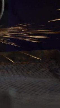 Slowmotion of worker grinding metal with a grinder and cleaning the steel seam. Working in a metal processing workshop. The man works with an electric tool. Sparks from metal heating.