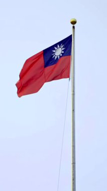 Vertical Slow motion of Taiwan flag waving high on a tall pole against the sky, symbolizing freedom and independence in Taiwan.