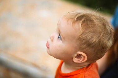Bahçedeki kum havuzunun arka planında küçük bir çocuğun portresi.