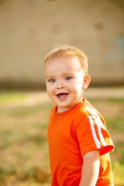 Parkta çimlerle koşuşturup gülen sevimli, mutlu sarışın çocuk, çocukluk konsepti.