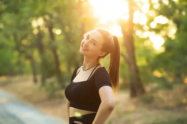 portrait of happy sports in forest summer park at sunset. Girl exercising on nature, health care and beauty concept