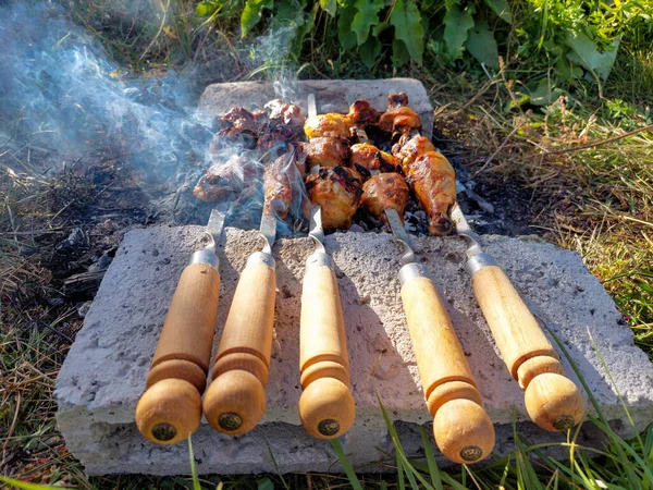 Shish kebab of chicken legs on skewers. Chicken meat on skewers. The smoke from the coals. Cooking in nature. Kebab of meat products.