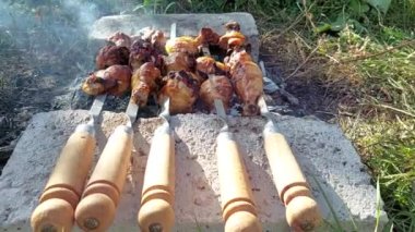 Shish kebab of chicken legs on skewers. Chicken meat on skewers. The smoke from the coals. Cooking in nature. Kebab of meat products.