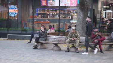 Kharkiv, Ukrayna, 27 Ekim 2021. Şehir merkezindeki bankta oturan insanlar. Huzurlu ve rahatlatıcı bir yaşam tarzı. Okumak ve telefonla konuşmak. Kasaba kafesi. Savaştan önce Harkiv. Yüksek kalite 4k görüntü