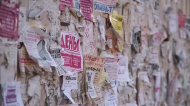 Kharkiv, Ukrayna, 27 Ekim 2021. Tahtayı caddeye çevirin. Duvardaki yırtık kağıt reklamları. Birisi bir kağıt parçasını telefon numarasıyla yırtıyor. Harkiv savaş öncesi. Yüksek kalite 4k görüntü