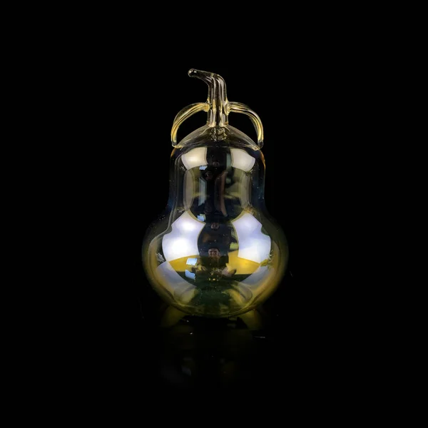 glass yellow pear on a black isolated background. antique figurine of a pear