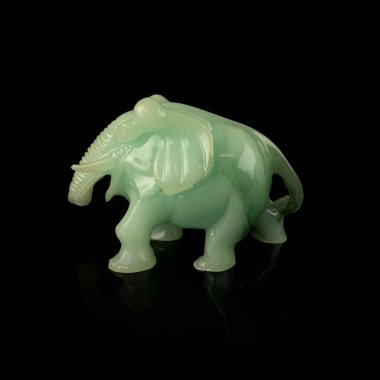 Green elephant figurine isolated on black background, close-up. antique porcelain figurine of an elephant