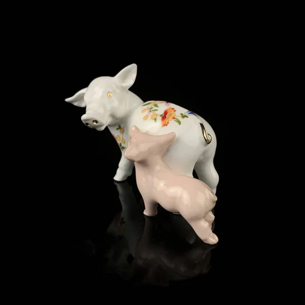 Pig ceramic figurine isolated on black background, clipping path included. antique porcelain figurine of pigs