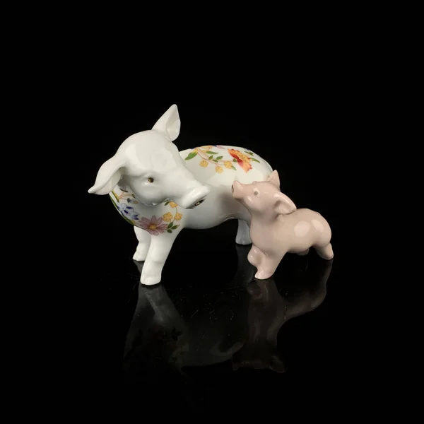 Pig ceramic figurine isolated on black background, clipping path included. antique porcelain figurine of pigs