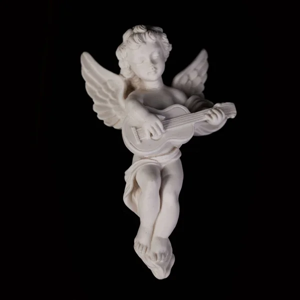 Angel figurine isolated on black background. Cupid with bow and arrow. Antique porcelain cupid figurine close-up