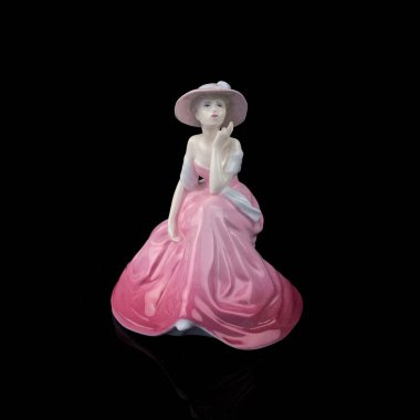 Vintage porcelain figurine of a woman in a long  pink dress on a black background.