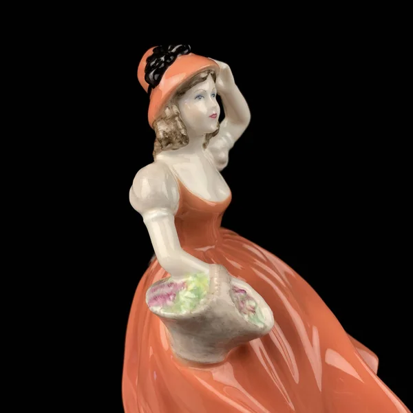 Sculpture of a woman in a red dress on a black background. antique figurine of a woman in a retro dress