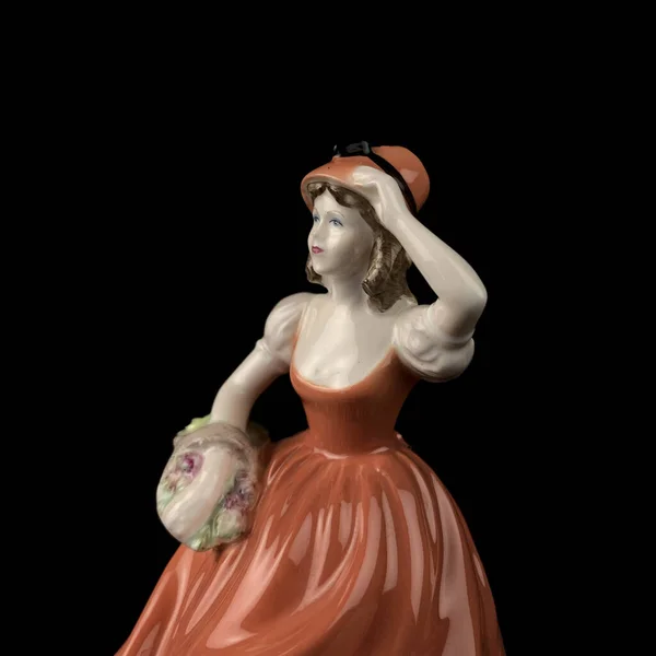 Sculpture of a woman in a red dress on a black background. antique figurine of a woman in a retro dress