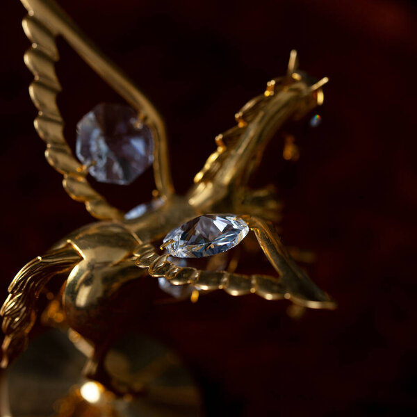antique gold figurine of a horse in a luxurious interior. golden pegasus on a dark background close-up, macro photography