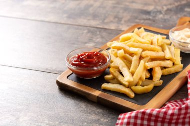Fried potatoes with ketchup and Mayonnaise on wooden table. Copy space