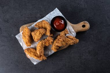 Siyah arka planda kızarmış Kentucky tavuğu.