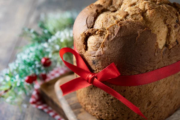 Geleneksel Noel panettonu ve ahşap masa üzerinde kırmızı kravat. Kapat.