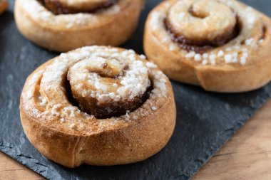 Tarçınlı çörekler ahşap masada. Kanelbulle İsveç tatlısı