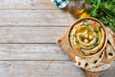 Ahşap masada maydanoz, kırmızı biber ve zeytinyağıyla süslenmiş ahşap bir kasede nohut. Üst Manzara. Boşluğu kopyala