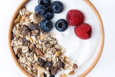 Kahvaltı için böğürtlenli yoğurt ve müsli beyaz arka planda izole edilmiş kasede. Kapat.
