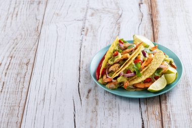 Mexican tacos with shrimp,guacamole and vegetables on wooden table. Copy space