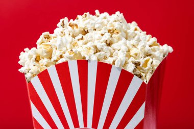 Salted popcorn on red background. Close up