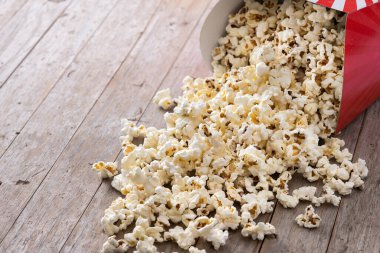 Salted popcorn scattered on wooden table. Copy space