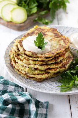 Beyaz ahşap masada yoğurt soslu kabak böreği.