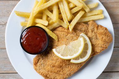 Wiener schnitzel with fried potatoes on wooedn table