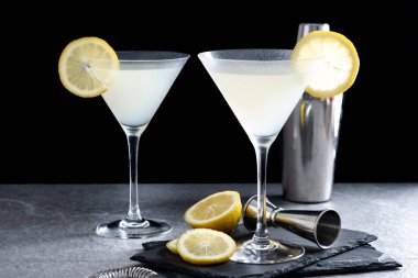 Lemon drop martini cocktail on gray stone and black background