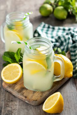 Kavanoz bardakta limonata ve ahşap masadaki malzemeler.