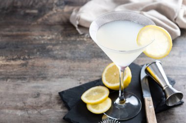 Lemon drop martini cocktail on gray stone and black background. Copy space