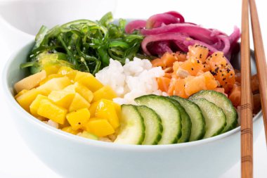 Poke bowl with rice, salmon,cucumber,mango,onion,wakame salad, poppy seeds ands sunflowers seeds isolated on white background