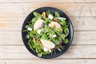 Ahşap masada elmalı ve cevizli sonbahar salatası. Üst görünüm