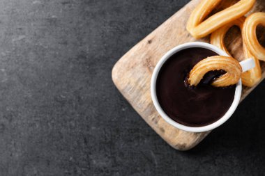 Siyah arkaplanda sıcak çikolata olan geleneksel İspanyol churro 'ları. Üst Manzara. Boşluğu kopyala