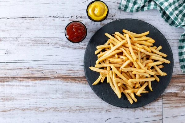 stock image Fried potatoes, french fries on wooden table. Top view. Copy space