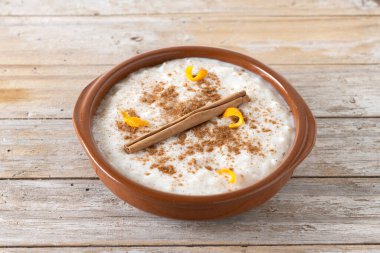 Arroz con leche. Tahta masadaki kil kasede tarçınlı sütlaç.