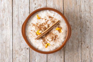 Arroz con leche. Tahta masadaki kil kasede tarçınlı sütlaç.