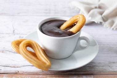 Geleneksel İspanyol churro 'ları sıcak çikolatalı kahvaltı ve ahşap masa.